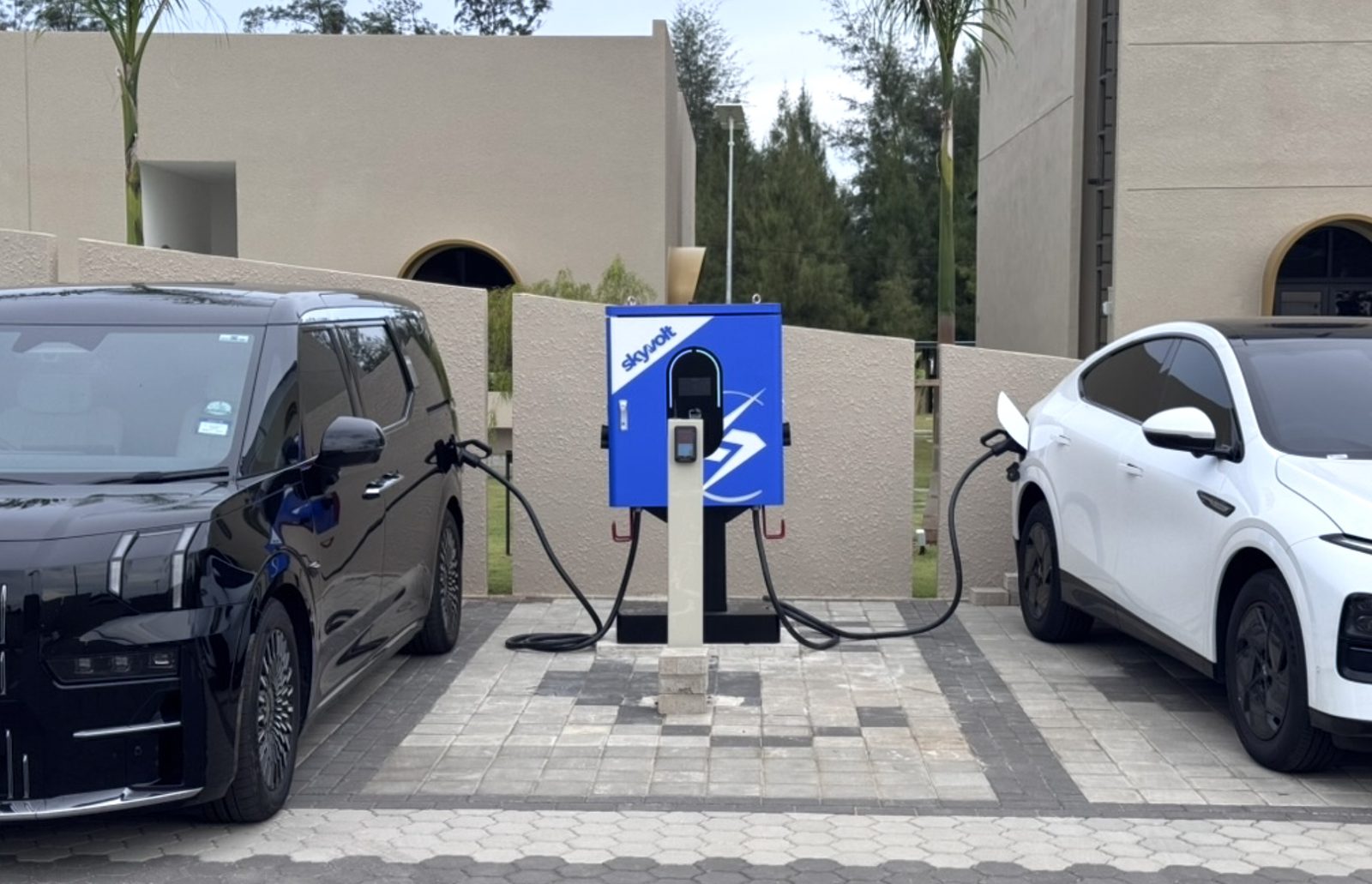 SkyVolt EV charger installed between two electric vehicles in a residential driveway